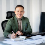 Adwokat Grzegorz Walerjańczyk siedziący przy biurku podpisujacy papiery