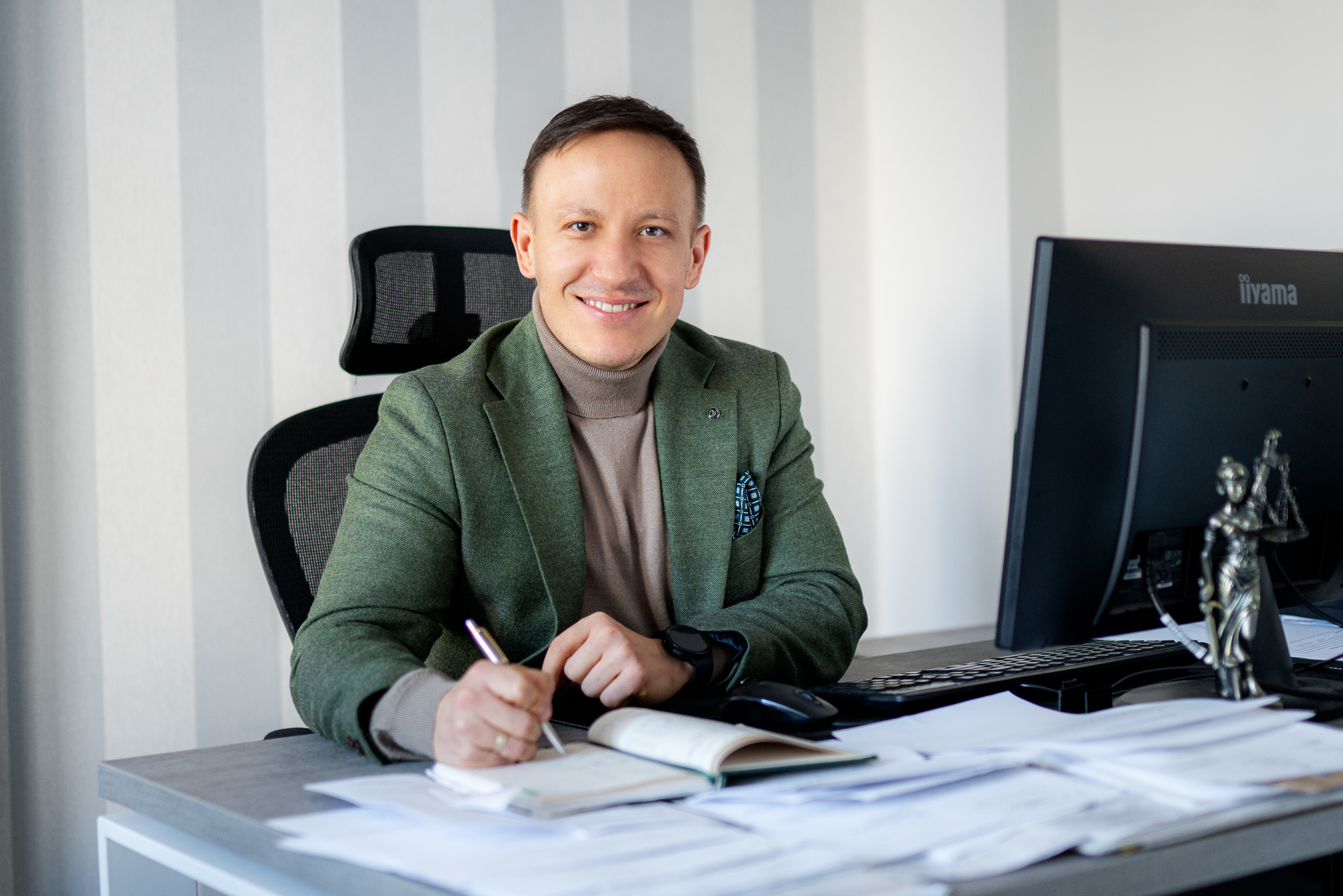 Adwokat Grzegorz Walerjańczyk siedziący przy biurku podpisujacy papiery