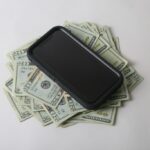 Smartfon leżący na stosie banknotów - prawo karne i cywilne dla osób fizycznych